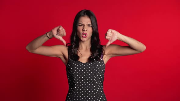 Woman Standing Red Background Expressing Discontent,showing Thumb Down Gesture