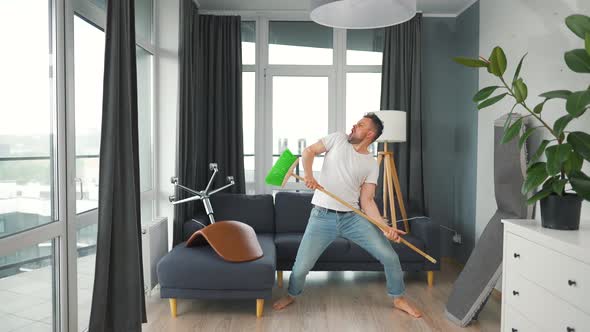 Man Does the Cleaning and Imagines Himself a Rock Star Plays the Broom Like a Guitar