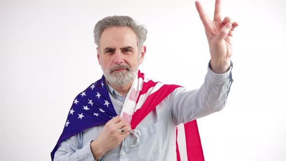 Aged Caucasian Man Shows Peace Sign While Having USA Flag on His Shoulders Medium Closeup White