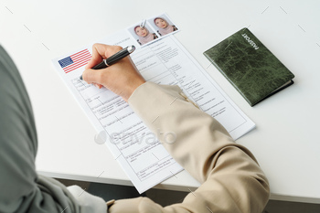 ting at desk with passport on it filling in visa application form
