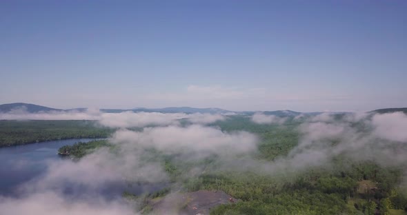 Flying Over White Puffy Low Clouds Over Wooded Lake Wassookeag in Maine