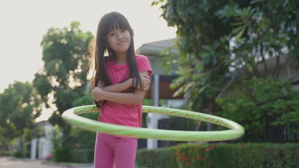 Young Asian little girl playing hulahoop exercise outdoor at home for health care and wellbeing.