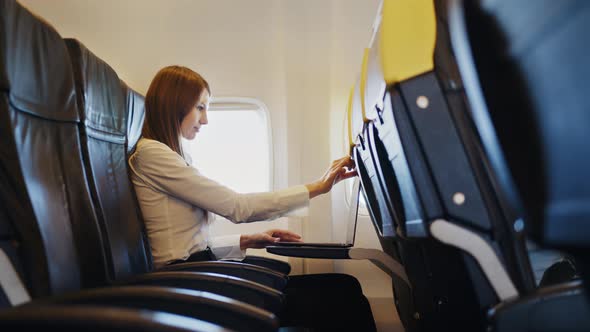 Side View of Woman Using Laptop for Work Inside Airplane