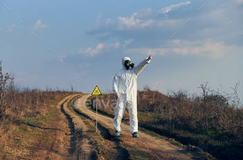 triangle with skull and crossbones warning sign and pointing finger at sky. Research scientist wearing protective suit, gas mask and shoe covers.