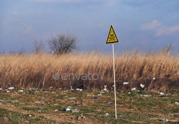 n abandoned territory with trash. Garbage waste field with toxic hazard sign. Concept of ecology, environmental pollution and hazard.