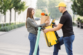 received the parcel delivery with organic fresh vegetables to to place of living. A man with yellow cap and backpack giving a package to a young woman