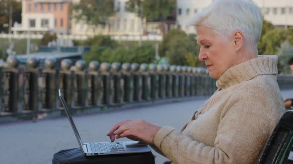 Elderly Woman of Retirement Age Typing on Computer Looking for Goods Buying Shopping Online