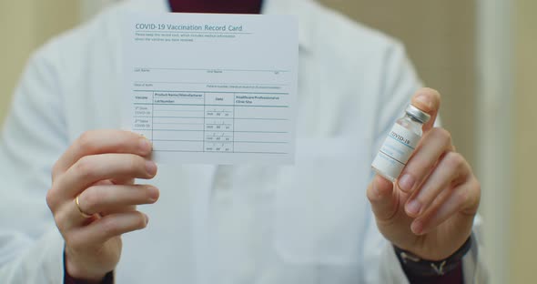 Doctor Is Holding a Vaccination Record Card and Corona Virus Vaccine Vials