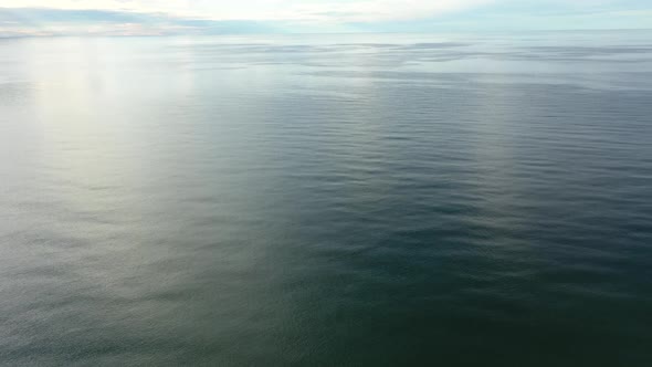 AERIAL: Rotating Shot of Vast Ocean with Blue Sky Horizon 