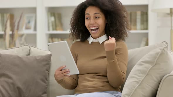Success Young African Woman Celebrating On Tablet on Sofa