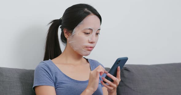 Woman apply paper mask on face  and use of mobile phone