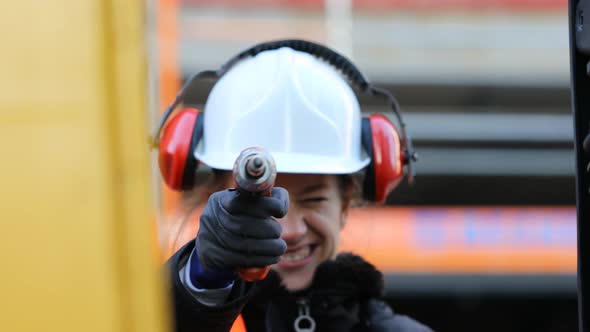 Smiling female technician holding drill and looking at camera