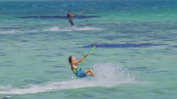 Young Kiteboarder Surfing in Mauritius Jumps While Riding Around the Turquoise Lagoon