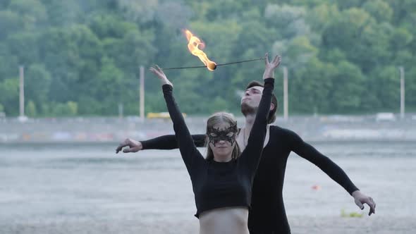 Young Beautiful Girl and Handsome Man in Black Clothes Performing Show with Flame Standing