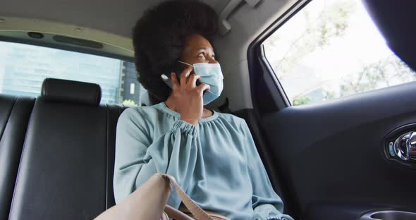 African american businesswoman with face mask talking on smartphone