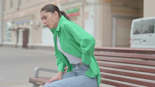 Hispanic Woman Having Back Pain While Sitting on Bench Outdoor