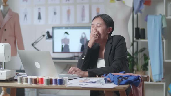 Asian Female Designer In Business Suit Working On A Laptop, Yawning, And Sleeping While Designing 