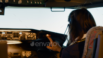 Woman copilot in uniform preparing to takeoff for airline flight