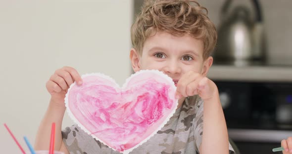 Close Up of a Little Boy's Who Just Cut and Draw a Red Heart with Watercolors and Present It to