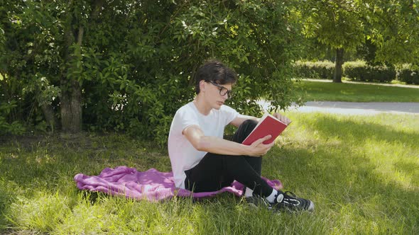 Young Man Reading the Book in the Park 