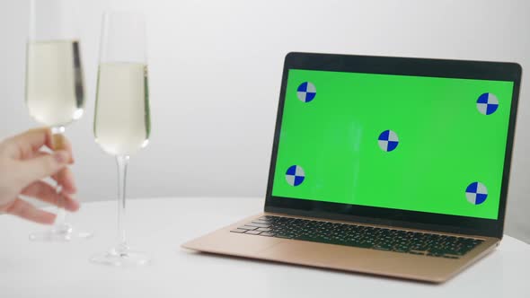 Closeup Chromakey Laptop with Young Female Hand Clinking Champagne Leaving Two Glasses on Table