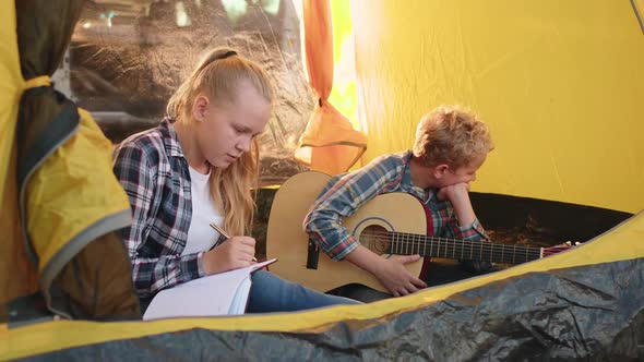 Teenager Girl and Boy with Guitar Sitting Inside Camping Tent in Forest. Girl Teenager Thinking