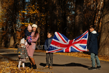 itish flags in autumn park.  Britishness celebrating UK. Mother with four kids.