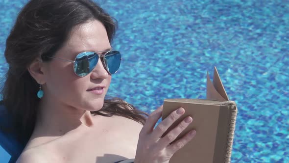 Beautiful Woman Relaxing With Book by Pool, Sunbathing at Beach