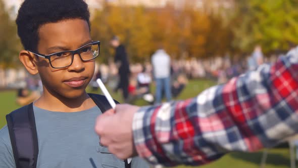 African Preteen Boy Refusing Cigarette Offered By Dealer Outdoors