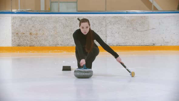 Curling Training - a Young Woman with Long Hair Pushes Off From the Stand - Leading the Stone Biter