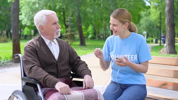 Happy Young Woman Giving Earphone Old Disabled Man, Supporting Hospital Patient