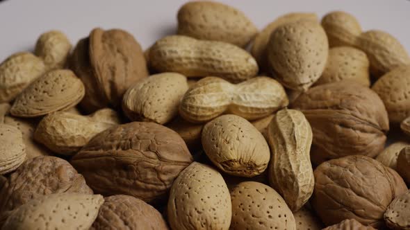 Cinematic, rotating shot of a variety of nuts on a white surface - NUTS MIXED