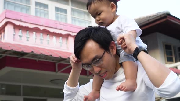 Asian Father Giving a Piggyback Ride for Little Son in Front of the House