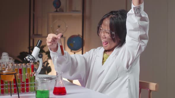 Excited Young Asian Scientist Girl With Dirty Face Mixes Chemicals In Test Tube