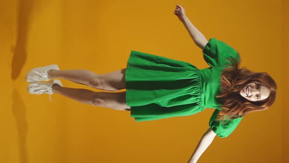 Cheerful Smiling Young Woman Jumps for Joy Like a Little Girl in a Studio Against an Isolated