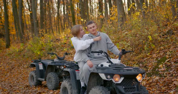 A Young Couple Rides an ATV Offroad in the Autumn Forest