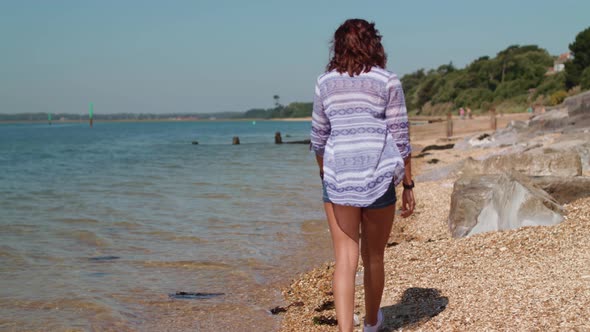 Young Woman Walks Along Beach and Picks Up Plastic Bottle In Slow Motion