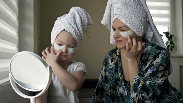 Beautiful Mother in Bathrobe and Her Little Daughter Together with Towels on Head and Mask on Face