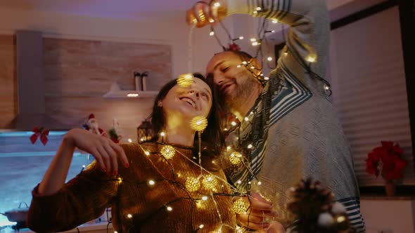 Man and Woman Tangled in Garland of Twinkle Lights