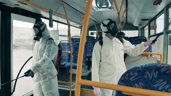 Two Workers Clean a Bus, Disinfecting From Coronavirus.