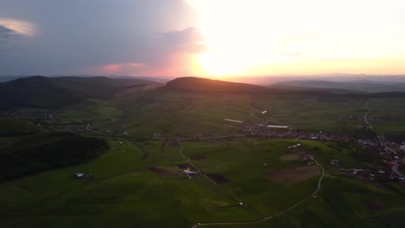 Panorama aerial shot of a beautiful sunset over open country with green meadows and fields, Transylv