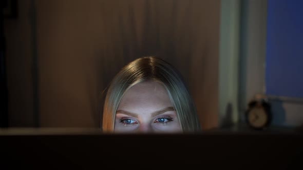 Woman Peeking Out Computer Monitor at Night. Crop View of Beautiful Female Sitting at Night at