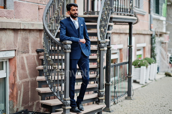 ear on blue suit posed outdoor against iron stairs.