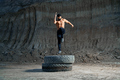 Handsome strong man jumping on wheel during evening workout - PhotoDune Item for Sale