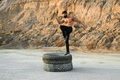 Athletic man in face mask training legs on tyres - PhotoDune Item for Sale