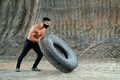 Young shirtless man moving large tyre outdoors - PhotoDune Item for Sale