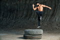Young shirtless man jumping on large wheel outdoors - PhotoDune Item for Sale