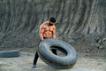 Bodybuilder in black mask doing exercises with large wheel - PhotoDune Item for Sale