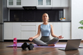 Attractive woman meditating at home and using laptop - PhotoDune Item for Sale