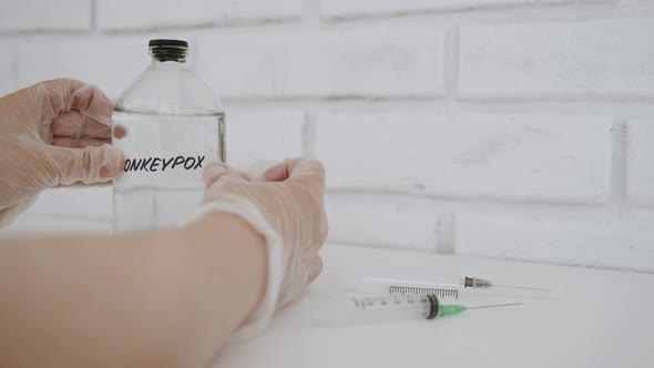 Hands in Gloves Glue Sticker with Inscription Monkeypox on Flask in Laboratory